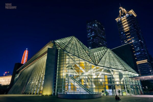 At night, Shenzhen’s modern, glass-walled library is aglow with light. Behind it, several large skyscrapers rise into the indigo sky.