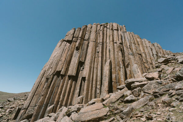 Against a bright blue sky, the majestic volcanic rock pillars of Shitiao Mountain in Inner Mongolia, China, tower like an enormous pipe organ constructed out of basalt.