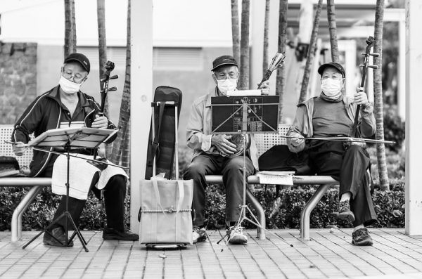Three musicians on a pair of public benches