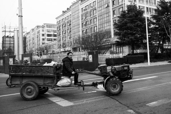 A man driving a skeletal, improvised-looking cargo vehicle, like a trailer being towed by an all-terrain lawnmower. It probably sounds like a flock of Harley Davidsons, and smells like an oil rig on fire. Sorry, I have no idea how to do this thing justice.