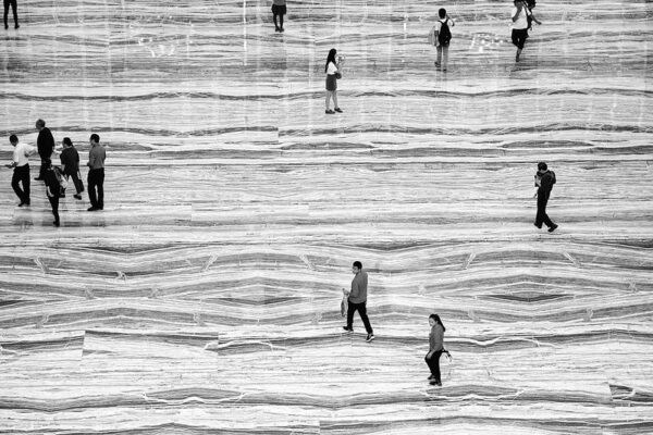 Seen from above, groups of passersby walking over a floor with wavy patterns look as if they are traveling along a river.