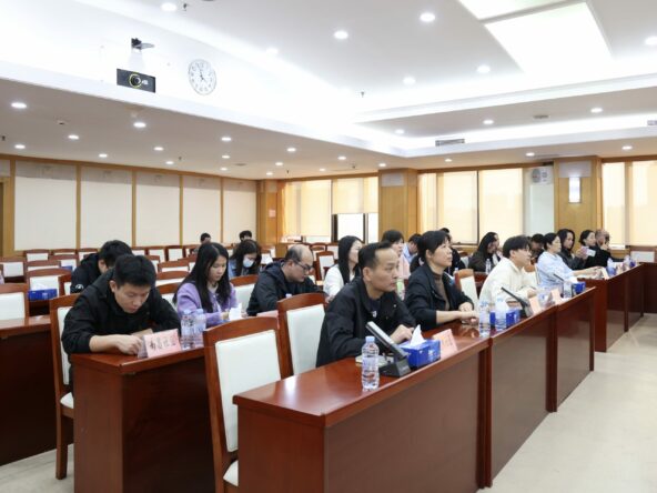 Chinese people sit at desks, watching a presentation occurring out of shot