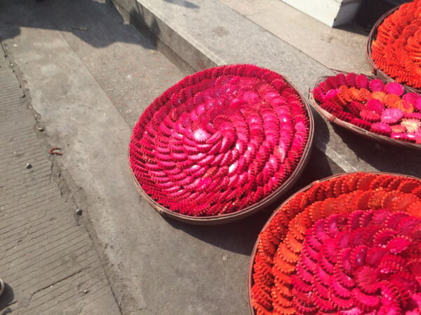 For the Qingming Festival in Quanzhou, Fujian province, several round bouquet-like platters of red and orange paper offerings have been placed on the ground.