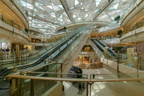 Escalators radiate outward from a central circular structure in the ultramodern IFC shopping mall in Shanghai’s Pudong district. On this particular day, there appear to be very few shoppers: just a few people, along with one or two security guards dressed in black.