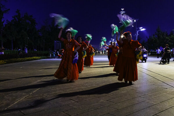At night, in a public square near the Beijing Bird’s Nest stadium, two lines of mainly middle-aged women are dancing. They are dressed in sparkly red dresses of different designs, and waving colorful scarves in the air with their right hands. All around them are other people also enjoying the evening—walking, riding bikes or mopeds, pushing strollers, or sitting on benches and chatting.
