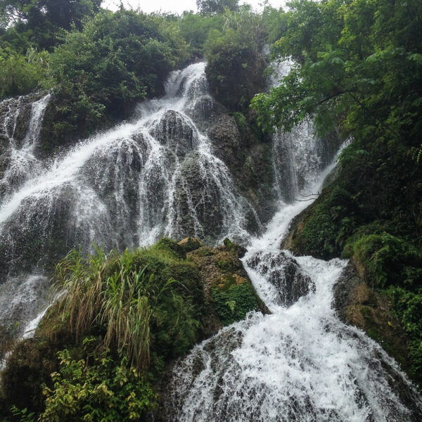 Myriad small waterfalls cascade down a lush green hillside in Xiaoqikong scenic area in Guizhou province, part of the South China Karst UNESCO World Heritage Site.