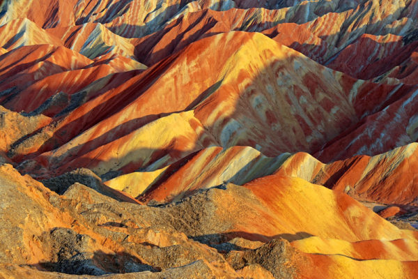 The spectacular Danxia (“red cloud”) landforms of Gansu Province look like undulating hills of marble, stretching away into the distance in hues of yellow, orange, and rust.